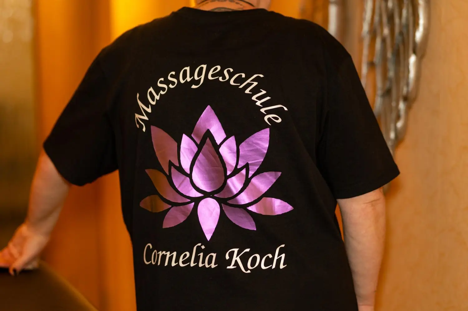 Massageschule Cornelia Koch mit Aufdruck auf der Rückseite eines T-Shirts
